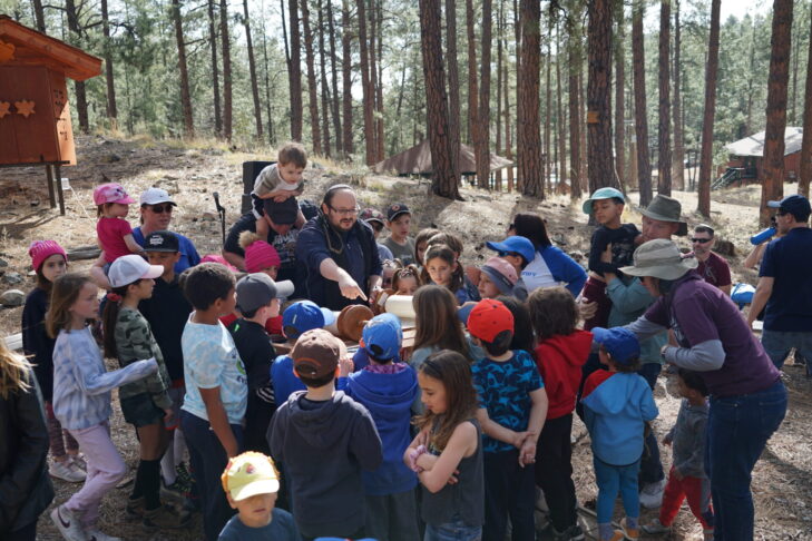 Photo of a group of children gathering around the Torah at Camp Daisy and harry Stein