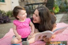 Stock image of a mom reading a book to a young child