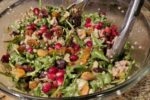 photo of a bowl of seven species salad including raisins, dates, pomegranate seeds, quinoa, barley, arugula, cucumber, and pistachios
