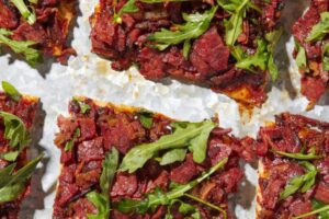 photo of square cuts of BBQ Pastrami Grilled pizza topped with arugula