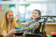 photo of an adult engaging with a child in a wheelchair