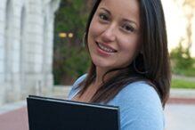 Stock image of a girl holding a book on a campus