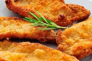 Photo of chicken schnitzel on a plate with rosemary garnish