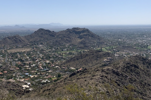Photo overlooking Phoenix from the summit of a hiking trail - greenery, homes in the valley, and mountains