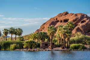 Photo of Papago Park - red rock mountains in the background of a lake with palm trees surrounding