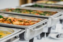 Stock image of catering trays with a variety of food in warming trays