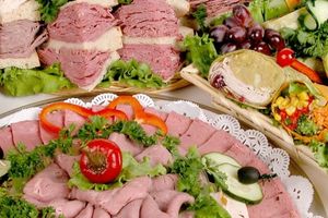 photo of a kosher deli platter with a variety of meats, sandwiches, fruit and veggies