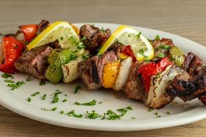 photo of kosher meat and vegetable kabobs on a plate with lemon and spices 