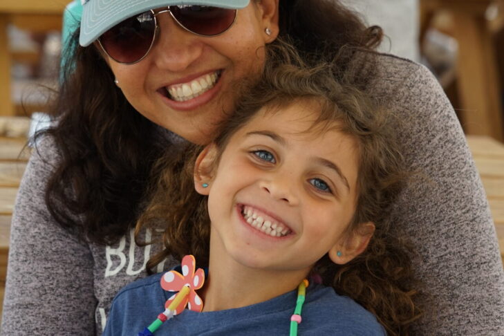 Photo of a mom hugging her smiling daughter at PJ Library Family Camp