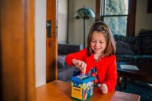 Stock image of a young girl putting a coin into a tzedakah box