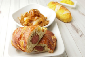Stock image of Pretzel Wrapped Brats with Cider Braised Onions