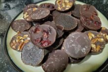 photo of a plate filled with a variety of homemade chocolate gelt including ones with dried fruit, sea salt, sprinkles and nuts