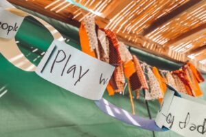 photo of a paper chain with written words on each link hung from the top of a sukkah