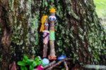 photo of a tree trunk covered in moss with two decorated sticks aka sukkah greeters leaning on the trunk