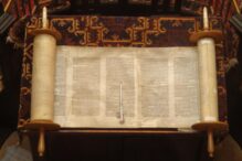 photo of an open Torah with a yad (pointer) sitting on top