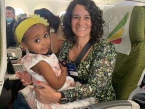 Photo of Danielle Gross holding her new friend, Elsa, on the flight from Ethiopia to Israel