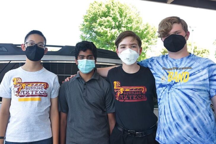 Image of four masked teenagers posing for a photo