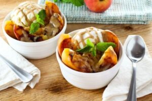 photo of two bowls of grilled peach sundae topped with brandy butterscotch sauce and topped with mint next to a spoon