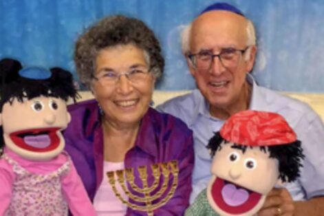photo of grandparents holding a menorah and puppets