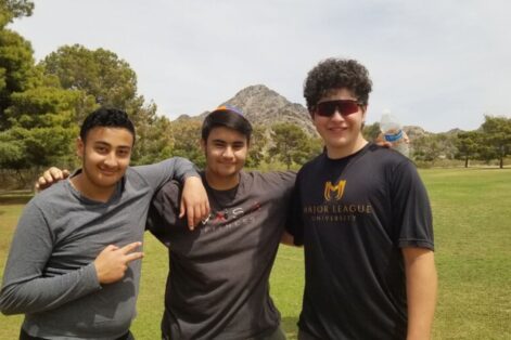 photo of three teen boys posing for the camera with mountains and trees in the background