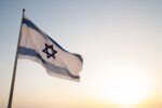 Photo of an Israeli flag waving in the wind with clear skies