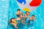 Image of a group of teens looking up at an incoming beach ball while playing in a pool