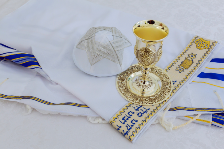 Image of a Kiddush cup and kippa sitting on a tallit