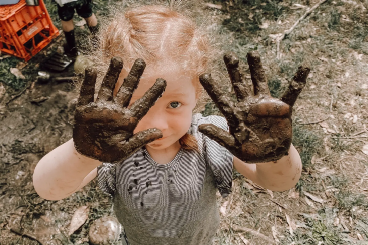 Child holding up muddy hands